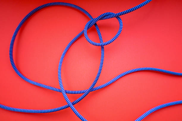 istock A blue rope with white stripes is tangled on a vibrant red background, forming a chaotic yet intriguing pattern. 2226763767
