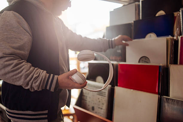 A male browses vintage vinyl records in a retro store with headphones in hands