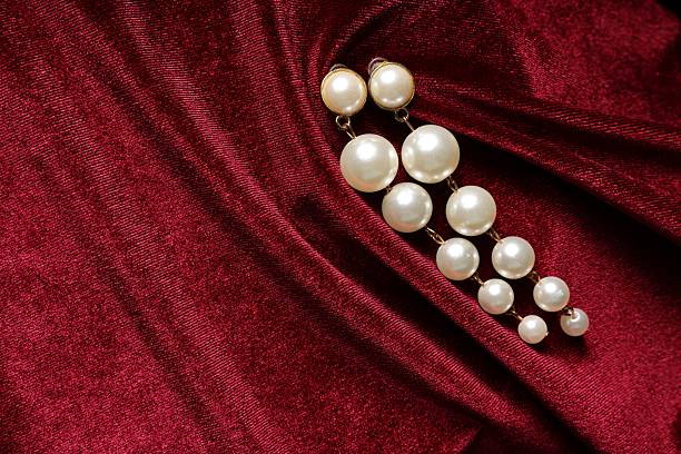 Beautiful pearl earrings on red cloth, top view. Space for text