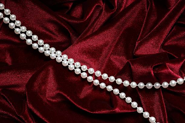 Beautiful pearl necklace on red cloth, top view