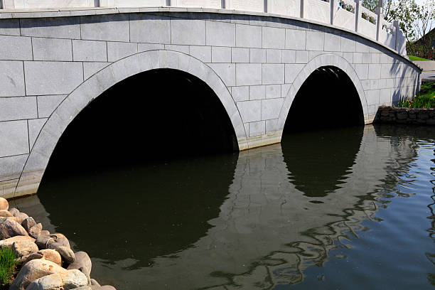 Stone arches of the old bridge reflected in the water of the Manzanares River, Madrid