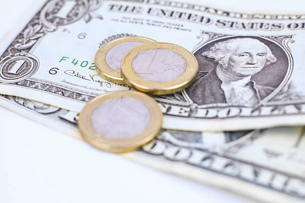 Three euro coins and dollar bills on white background
