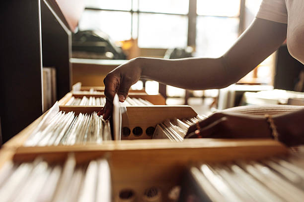 A close-up of a hand browsing through vinyl records in a retro store