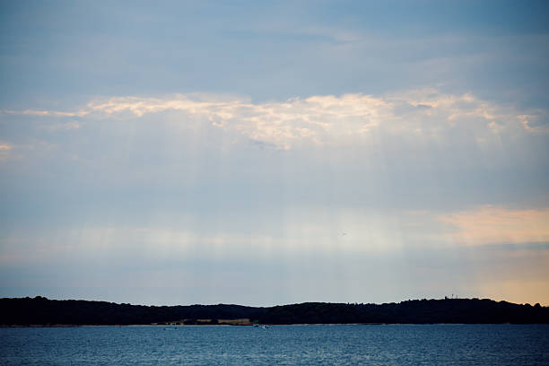 Beautiful sunset over the sea. Sun rays break through the clouds. Summer evening. Fazana, Croatia - circa 2025