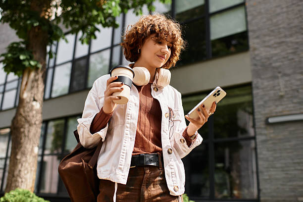 istock Young woman enjoys coffee while checking her phone outside modern office building 2226767726