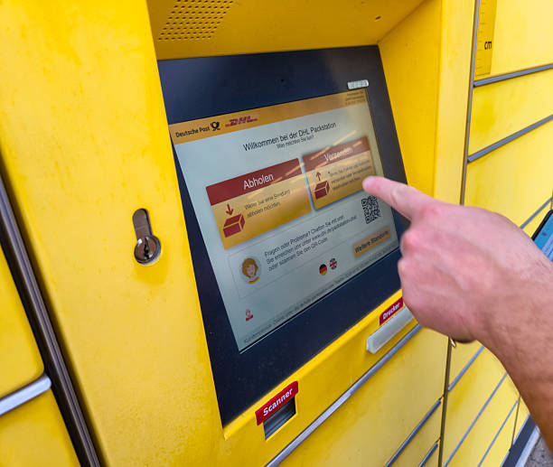 Lahde, Germany - April 15 2025: A user interacts with a DHL package station touchscreen to retrieve a parcel, showcasing modern logistics technology in urban settings.