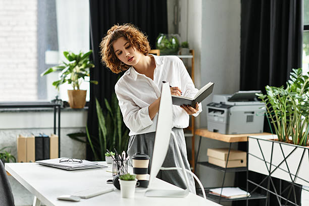 istock Young businesswoman reviews notes while working in a bright modern office space 2226777651