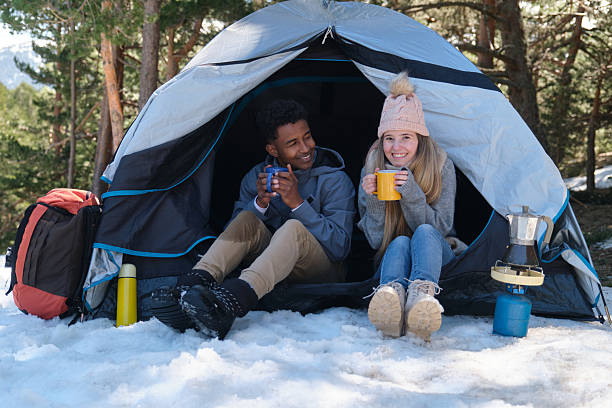 istock Young multi-ethnic couple camping and drinking hot beverages in snowy forest during wintertime 2226781387