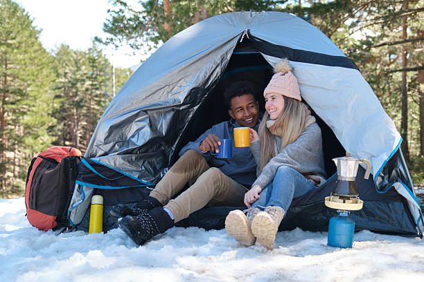 istock Happy couple camping and drinking hot drinks in winter forest 2226781645