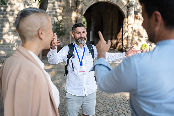 istock Tour guide gesturing while engaging with tourists near a historic stone structure 2226784768