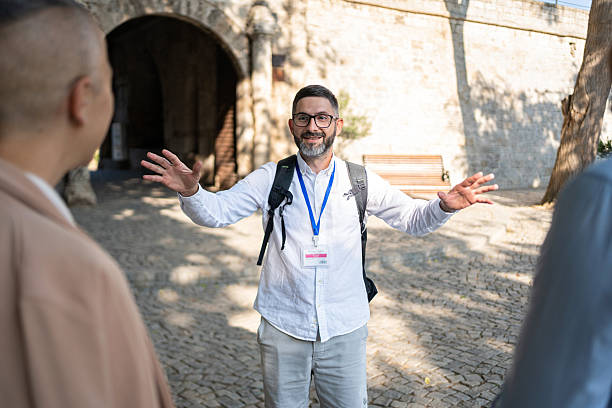 Mid-aged guide explaining historical landmarks to tourists near an ancient fort