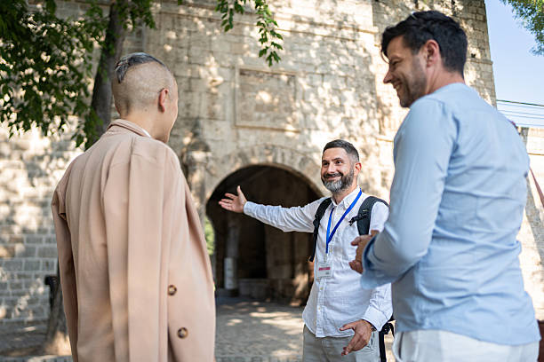 istock Experienced tour guide showing historical sights to two tourists by an ancient structure 2226785262