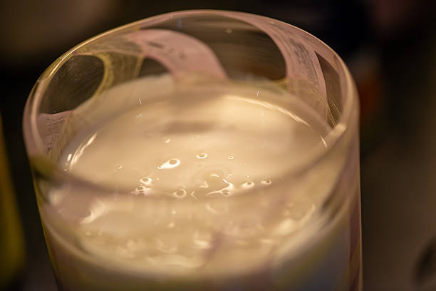 A clean, high-resolution photo of creamy white kefir being poured into a transparent glass.