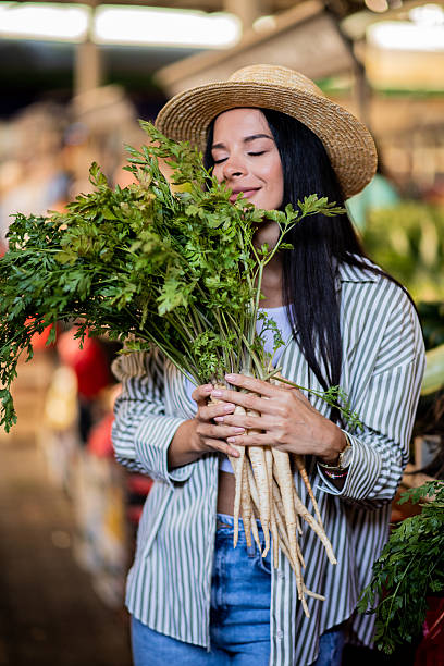 Young Woman Smelling Fresh Parsley at Market