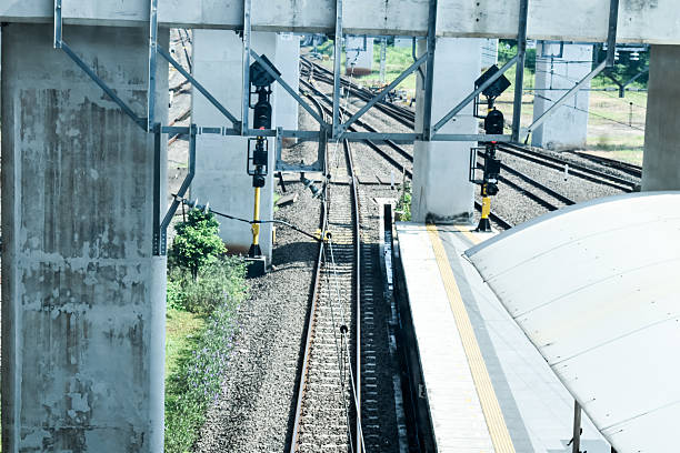 Train tracks beside platform at quiet station with overhead lines