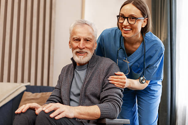istock Caring nurse assisting elderly man in wheelchair hugging looking at camera 2226789685