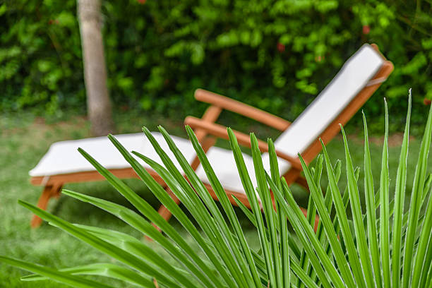 Two empty outdoor lounge chairs on sandy beach near blue water at sunny off-season day.