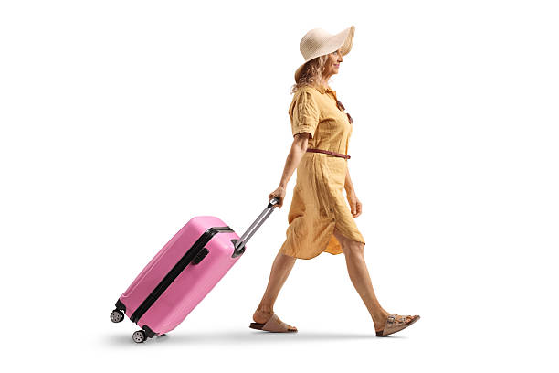 istock Mature woman walking and pulling a pink suitcase 2226794140