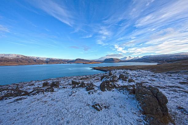 Still blue water and white hills around Icelandic fjord in winter