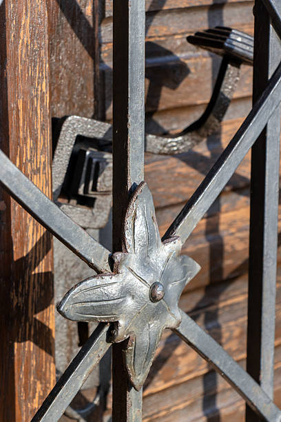 The old door with a wrought iron handle behind an iron lattice with decoration, close up.