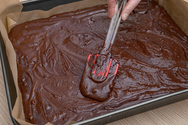 Overhead composition of rich chocolate bark decorated with walnuts, hazelnuts, and almonds. Small bowls filled with nuts and a textured black fabric set the tone for a cozy, rustic treat. The top-down perspective adds balance and provides open copy space to the right for branding or editorial use. A deliciously sweet moment captured in visual warmth.