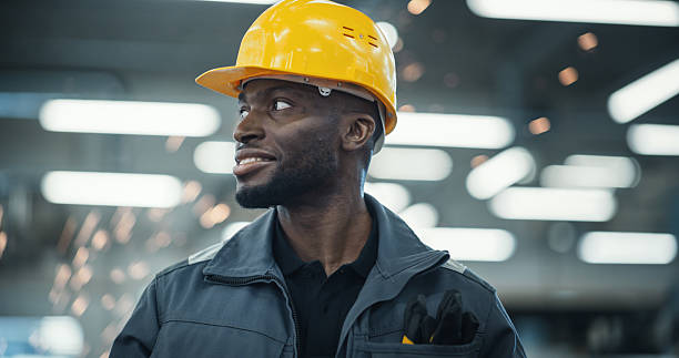 istock Smart Male Engineer in a Yellow Hard Hat Working in a Modern Metal Component Production Factory. Black Man Looking Around the Facility. 2226802387