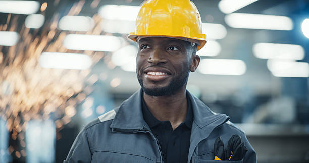 istock Smart Male Engineer in a Yellow Hard Hat Working in a Modern Metal Component Production Factory. Black Man Looking Around the Facility. 2226802936
