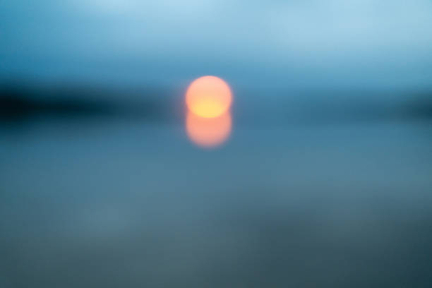 Peaceful blue sea with a distant golden sun setting on the horizon