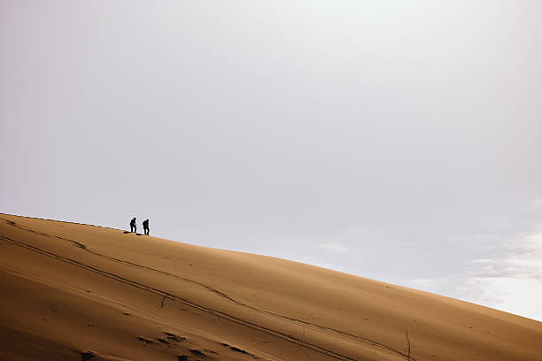 istock Two hikers walking on a sand dune in the desert 2226811460