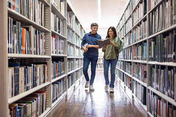 istock Happy students searching for a book at the library 2226813065
