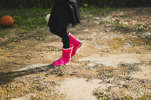 Child walking in mud with pink rubber boots at a pumpkin patch
