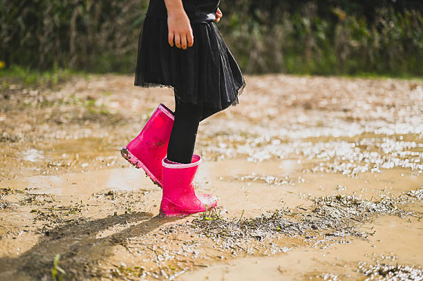 istock Child walking in mud with pink rubber boots 2226815614