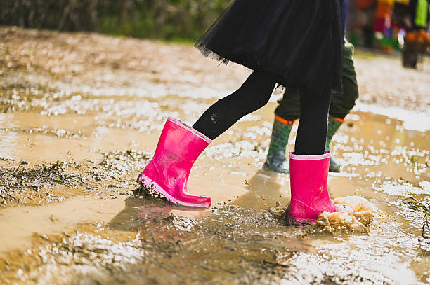 Two children having fun jumping in a muddy puddle