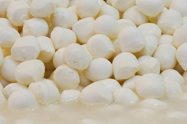 Plump mozzarella balls are arranged neatly in a market stall.