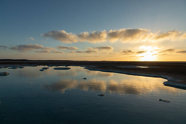 a lake with ice and a field with a lake in the background.