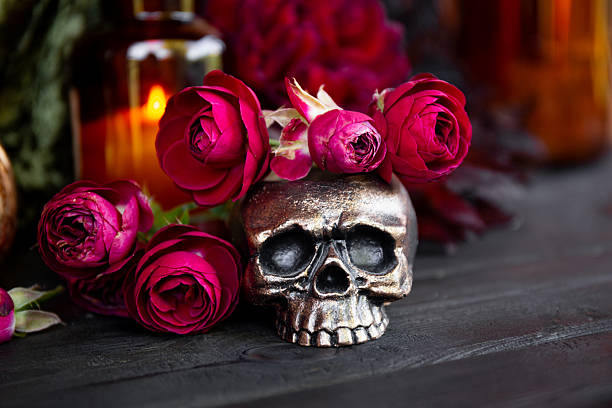 Skull with red roses on dark table, Halloween concept card. High quality photo