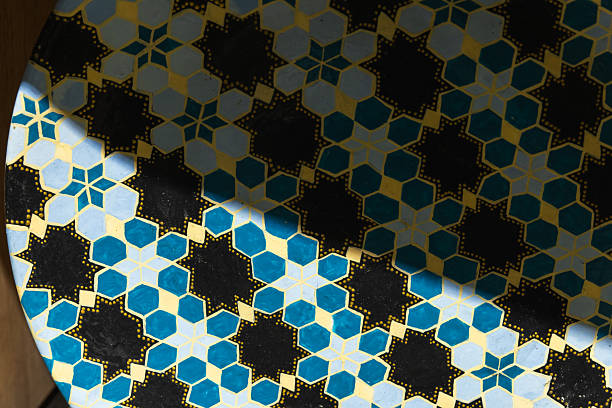 An artistic plate with an Islamic geometric tile pattern featuring blue, yellow, and black star and hexagonal shapes. Elegantly enhanced with partial sunlight, reflecting cultural heritage