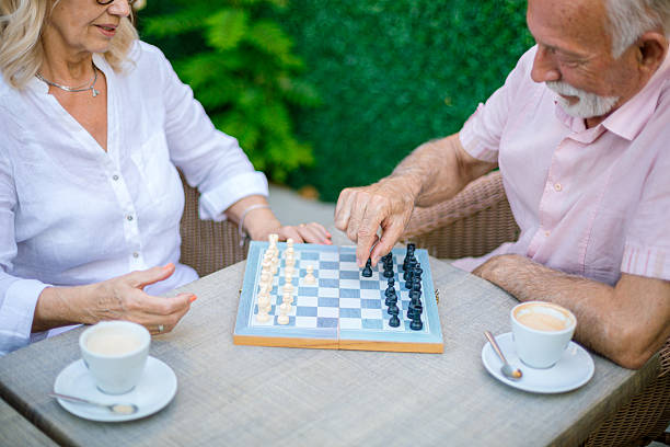 Elderly couple enjoying a game of chess and coffee at an outdoor cafe