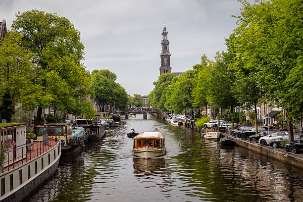 A tour boat travels down a canal on a beautiful summer day in Amsterdam, Netherlands (July 20, 2025)