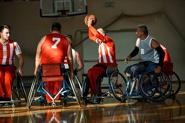 A dynamic wheelchair basketball match featuring diverse male players illuminated by warm sunlight on an indoor court.