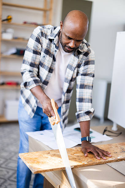 istock Carpenter sawing wood plank in workshop 2226834162