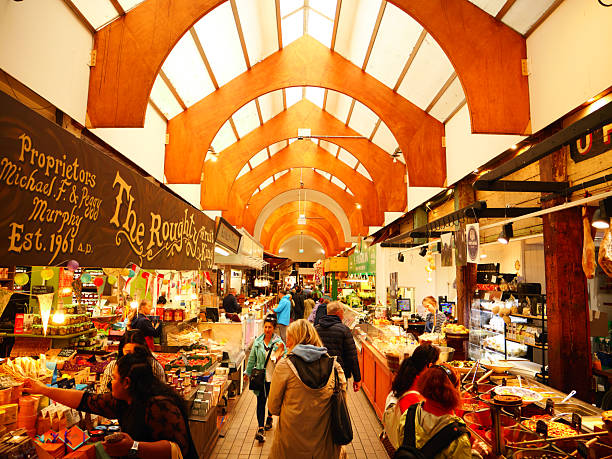 Cork, Ireland - May 27 2025: Shoppers browse bustling stalls inside Corks historic English Market, framed by arching wooden ceilings.