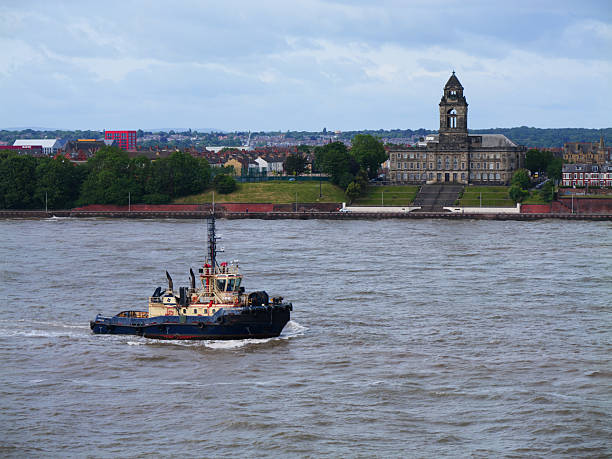 River Mersey, UK - May 26 2025: The tug Svitzer Amazonas navigates the River Mersey, with Wallasey Town Hall standing majestically in the background.