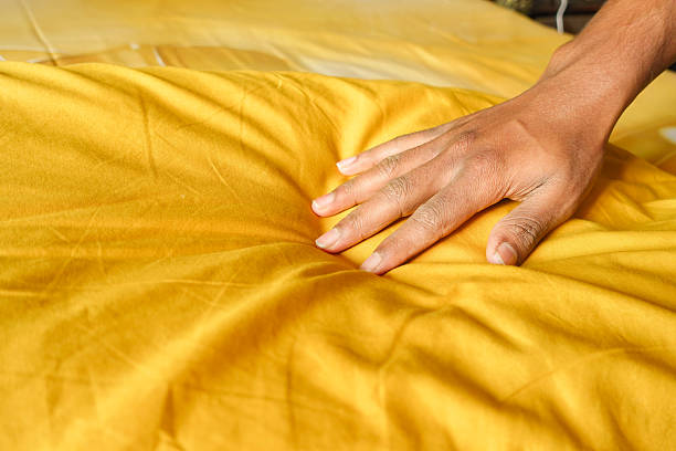 istock Hand gently pressing a soft yellow pillow on a cozy bed 2226839046