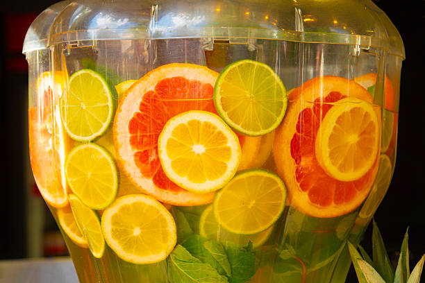 Refreshing citrus slices and mint in a clear drink dispenser, a summer vibe