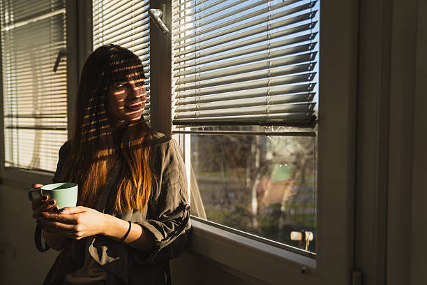 istock Beautiful young woman holding mug and looking out window 2226842085