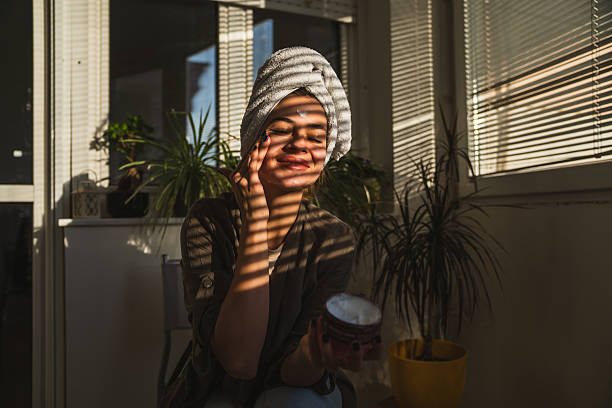 istock Young woman applying face cream and smiling in warm light 2226843213