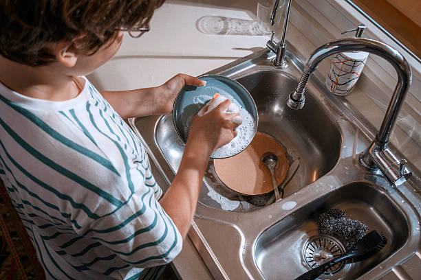 istock Young child washing dishes in kitchen sink 2226847332