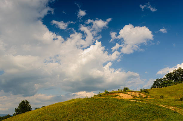 istock Sunny Hillside Landscape with a Bright Blue Sky and White Clouds 2226847665