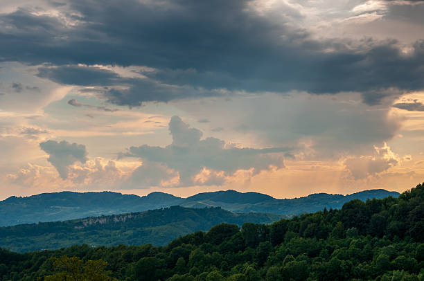 Sculpted sunset clouds glow above blue-green ridges, delivering depth via atmospheric haze. Works for adventure travel, environmental campaigns or inspirational quotes.